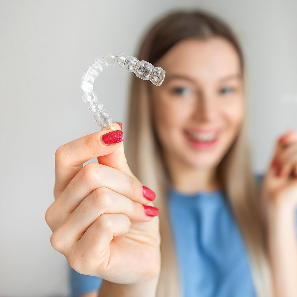 A person is holding up a small, clear plastic tray with a single toothbrush-shaped object inside it.